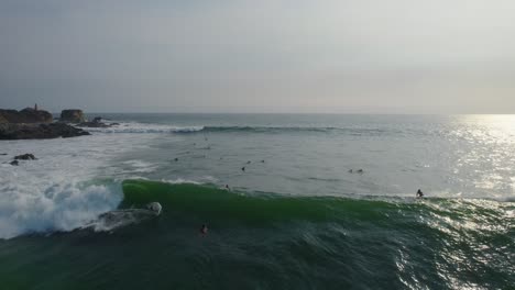 Vista-Aérea-Surfistas-Montando-Olas-Poderosas-En-Punta-Zicatela-Océano-Pacífico-Iluminado-Por-El-Sol-Paisaje-Marino-De-Oaxaca