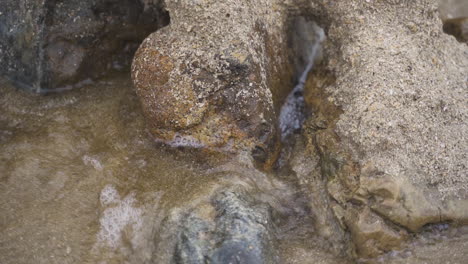 Rushing-water-splashing-through-sandy-structure-on-beach-slowmo