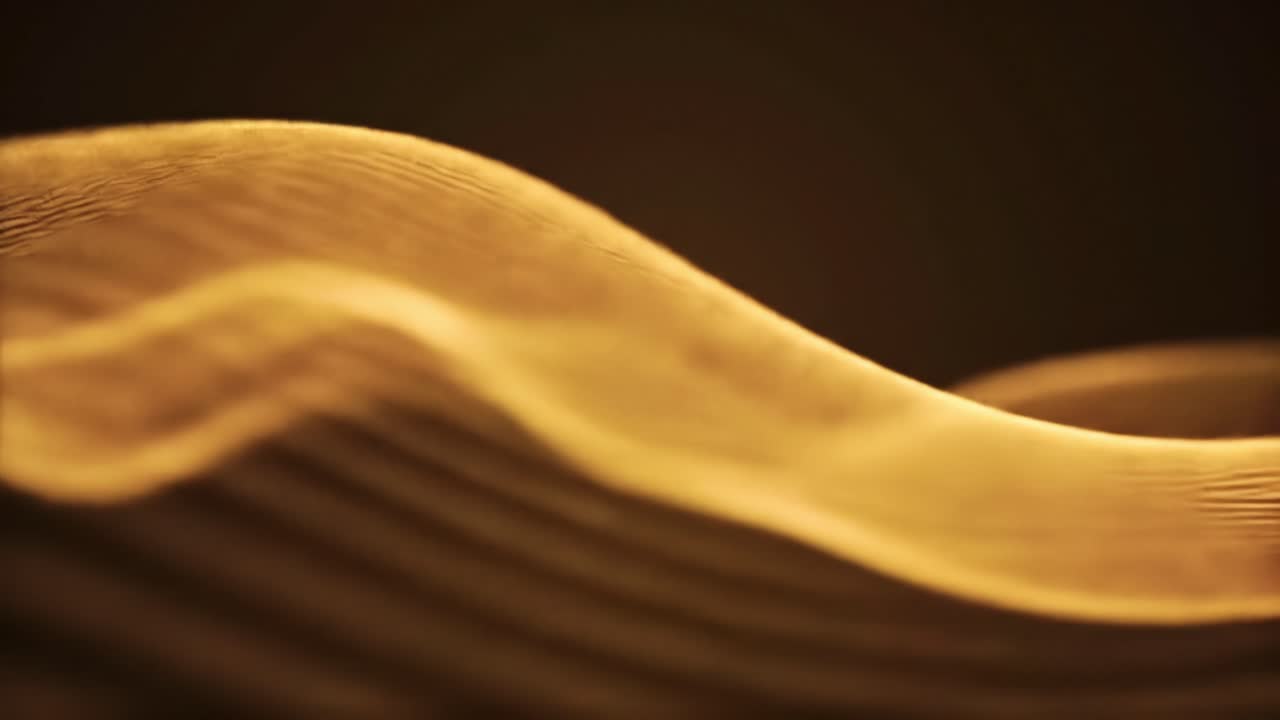 Light waves dance in captivating patterns, illuminating a dark space with warm gold tones. The flowing shapes shift and transform, creating a calming atmosphere.