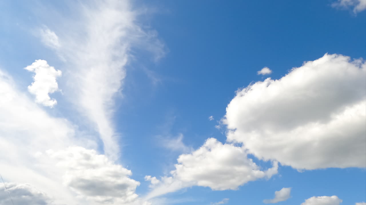 Sunny day clear skies covered with white clouds lit with bright sun. Beautiful soft cloudscape low angle view. Timelapse.