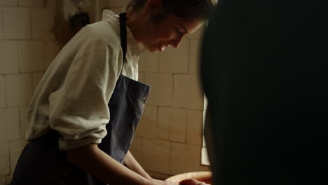 young woman learning to work with wet clay in pottery wheel