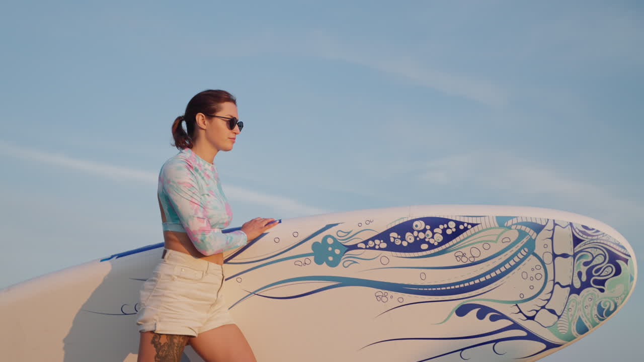 해가 지는 동안 서프보드 를 들고 있는 여자