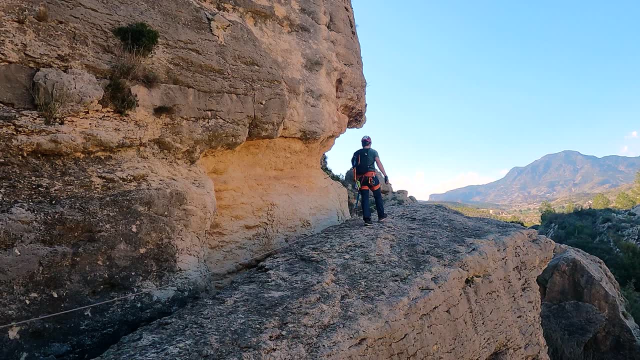 Person traversing a rocky path with climbing gear