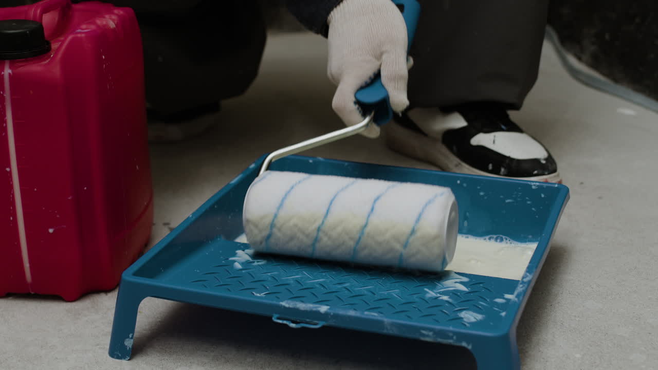 Close-up of a painter using a paint roller and tray