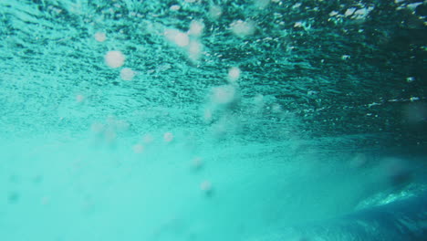 el surfista pasa por la línea mientras atrapa la clara ola de agua del océano, vista trasera