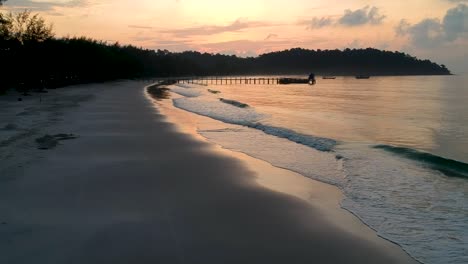 Relaxing-sunset,-colorful-sky,-calm-ocean,-pier-and-boat-on-the-beach