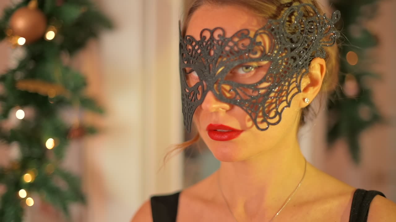 Primo piano di una donna con labbra rosse e occhi azzurri che indossa una maschera nera