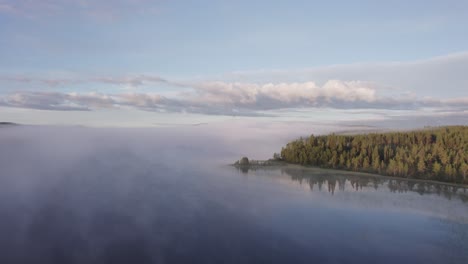 morning blue sky over misty calm lake scandanavian forest landscape drone push