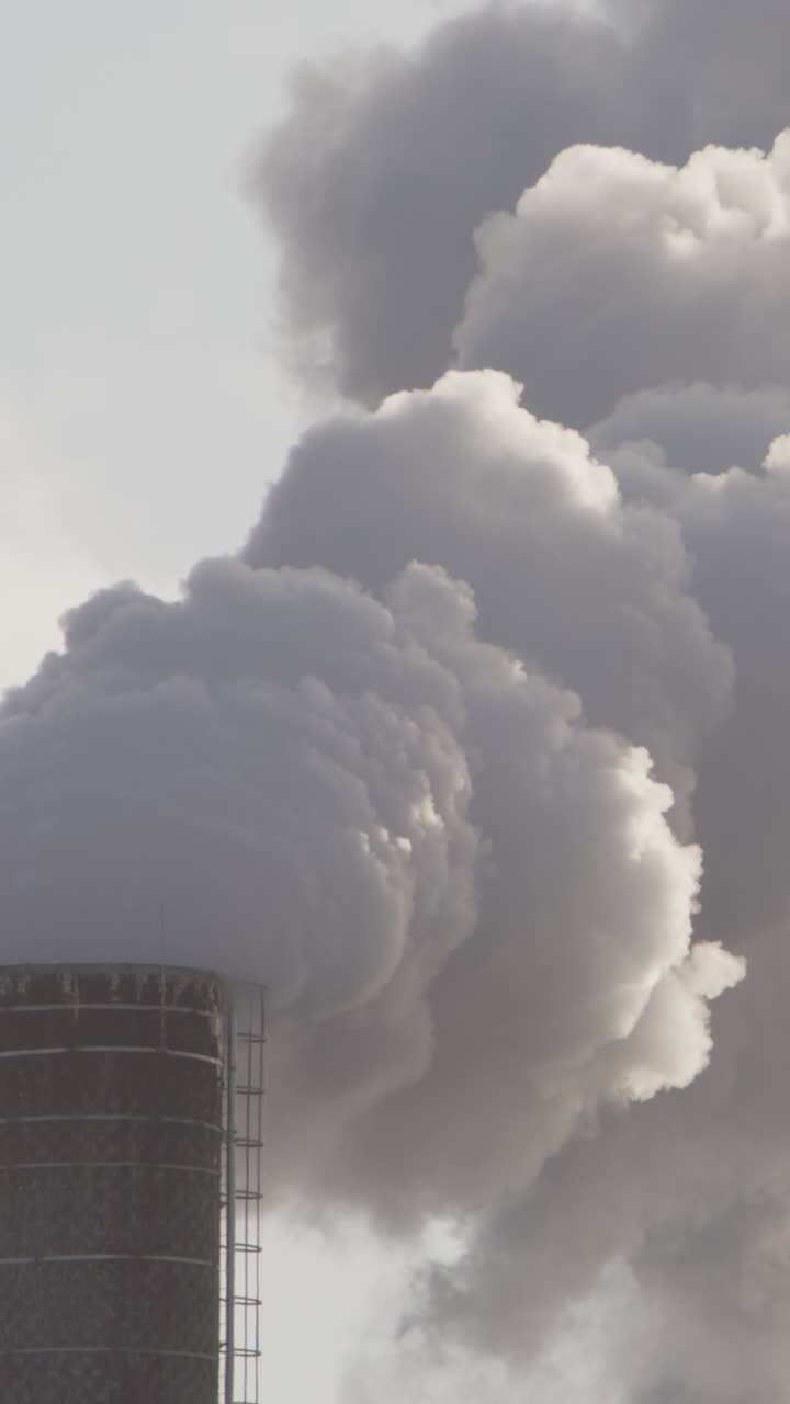 PANNING shot, billowing smoke from an industrial chimney, vertical
