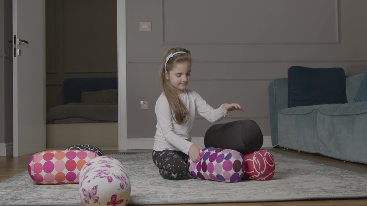 молодая девушка играет с подушками на полу
