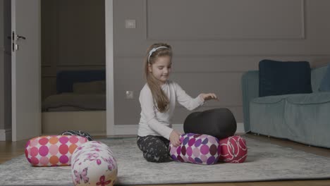 young girl playing around with cushions on floor