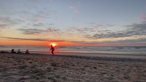 cielo dorado del atardecer sobre la playa con gente sentada en la orilla arenosa