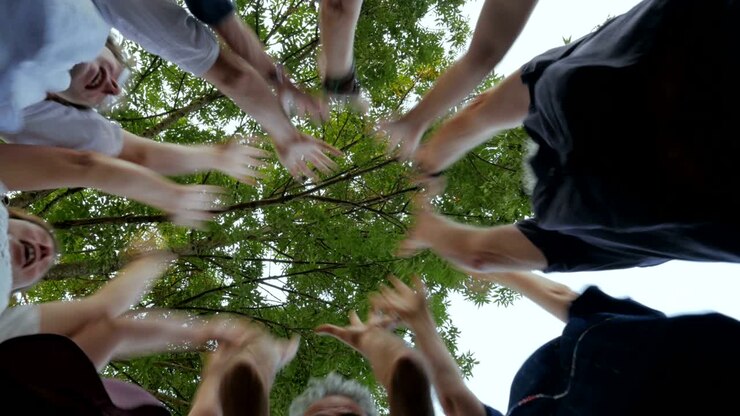 Multi generational group of people place their hands together in a circle