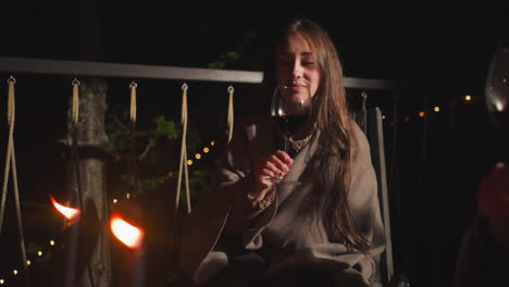 woman enjoying a glass of wine on a patio at night