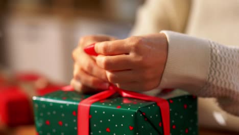 Hände-Packen-Weihnachtsgeschenke-Ein-Und-Binden-Schleife.-Feiertage,-Neujahr-Und-Weihnachtskonzept-–-Hände-Packen-Geschenkboxen-Ein-Und-Binden-Schleife-Zu-Hause-über-Schnee