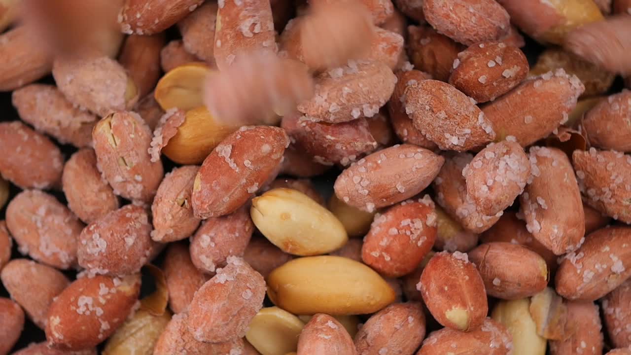 Solone orzeszki ziemne spadające na stos, zbliżenie