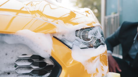 man washing a yellow car