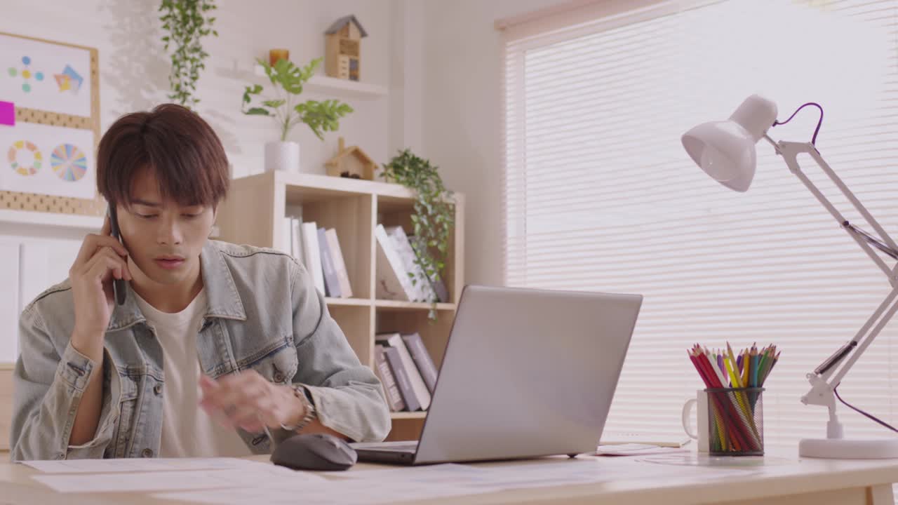 아시아인 디자이너는 스마트폰으로 커뮤니케이션을 하고, 프로젝트와 서류 작업을 하며, 노트북으로 책상에서 집에서 일합니다.