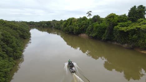 Aerial-View-of-Boat-in-Muddy-River-Deep-in-Jungle-of-Guyana,-South-America,-Tracking-Drone-Shot