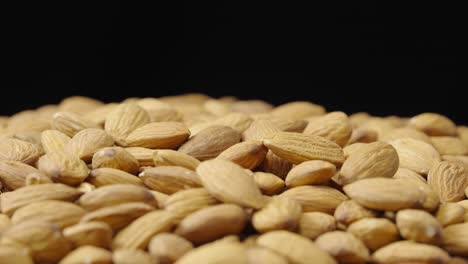 a close-up shot of a pile of raw almonds against a dark background
