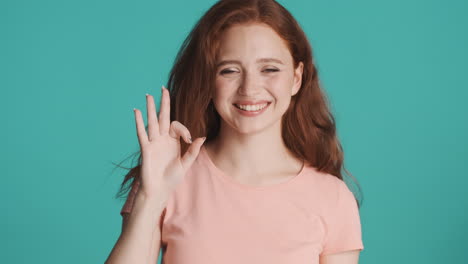 Redheaded-girl-looking-at-camera-on-turquoise-background.