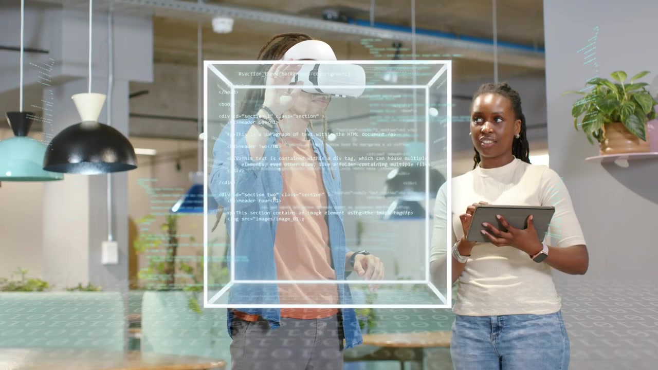 Woman tapping tablet initiating tech demo while man wearing VR headset manipulating wireframe cube