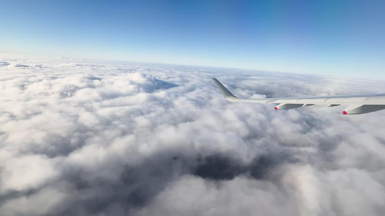 Højtliggende luftfoto af en jetvinge, der flyver over et tykt skylag