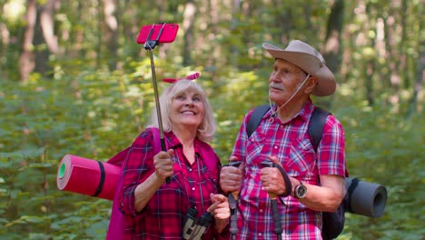 Senior-grandmother-grandfather-blogger-tourists-taking-selfie-photo-portrait-on-mobile-phone-in-wood