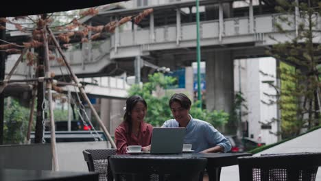 couple working on laptop in outdoor cafe