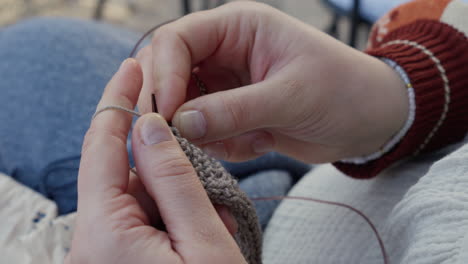 primer plano de manos crochetando con un hilo marrón en un día acogedor