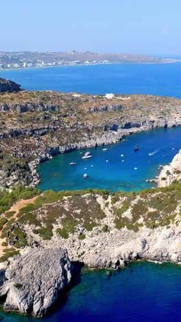 vertical drone shot orbiting the anthony quinn bay, sunny day in rhodes, greece
