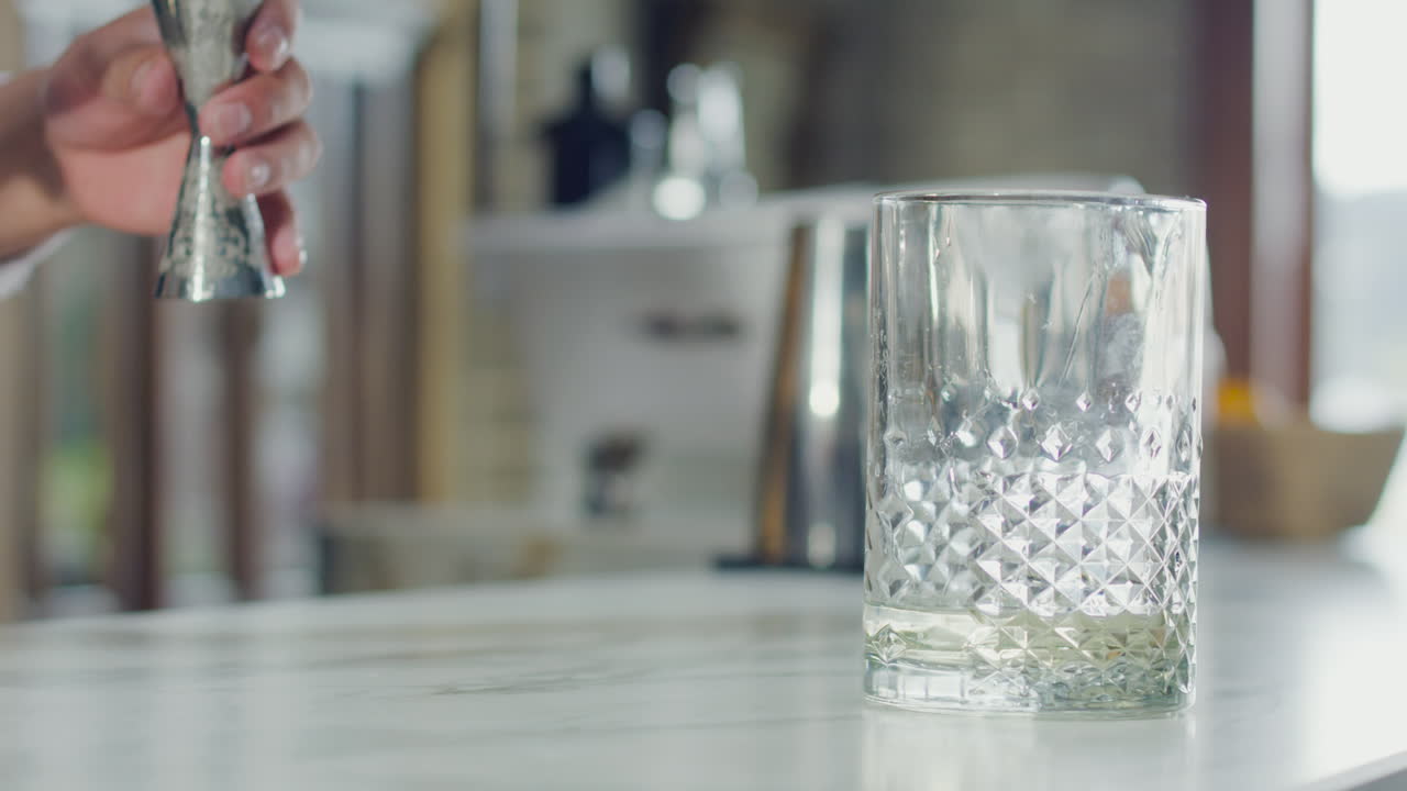 Alcoholic beverage being poured into a glass on a white bar in an elegant bar