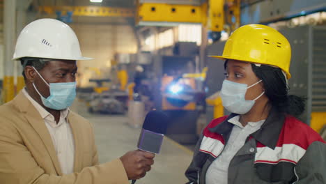 tv reporter in mask interviewing female factory technician