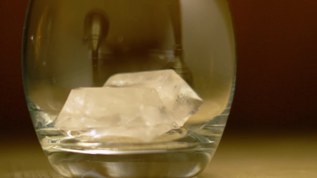Close Up of Ice Cubes Falling into Tumbler Glass in Slow Motion Ready to Add Beverage of Choice.