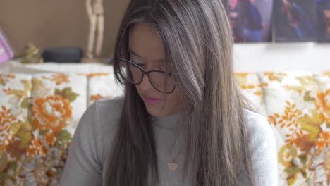 Woman-in-black-glasses-looks-down-while-working-with-her-hands-then-gazes-up