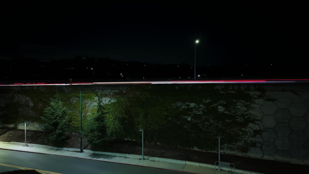 Right to left time-lapse captures evening traffic flowing along Walnut Creek’s highway, viewed from above as light trails weave through the city under a soft twilight sky