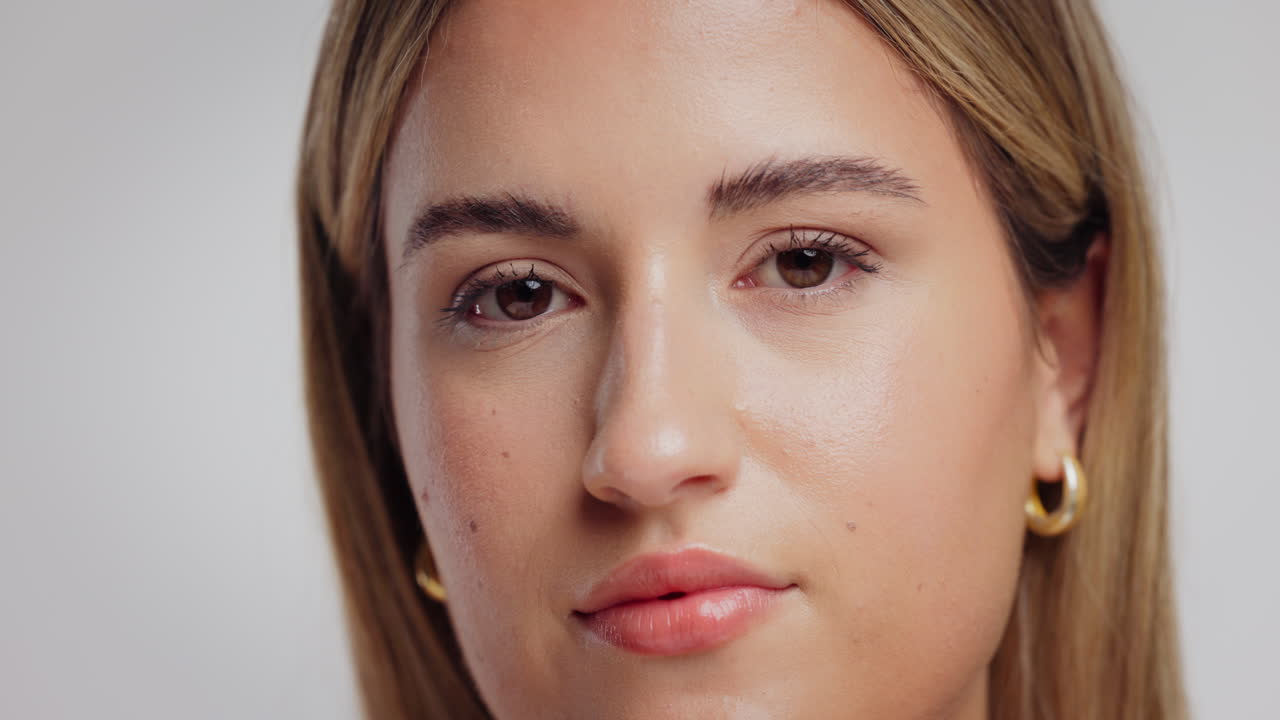 Woman holding a slice of cucumber over her eye