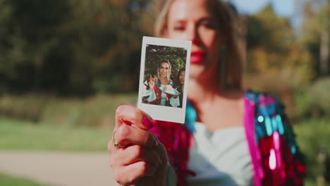woman in park with photo print and phone