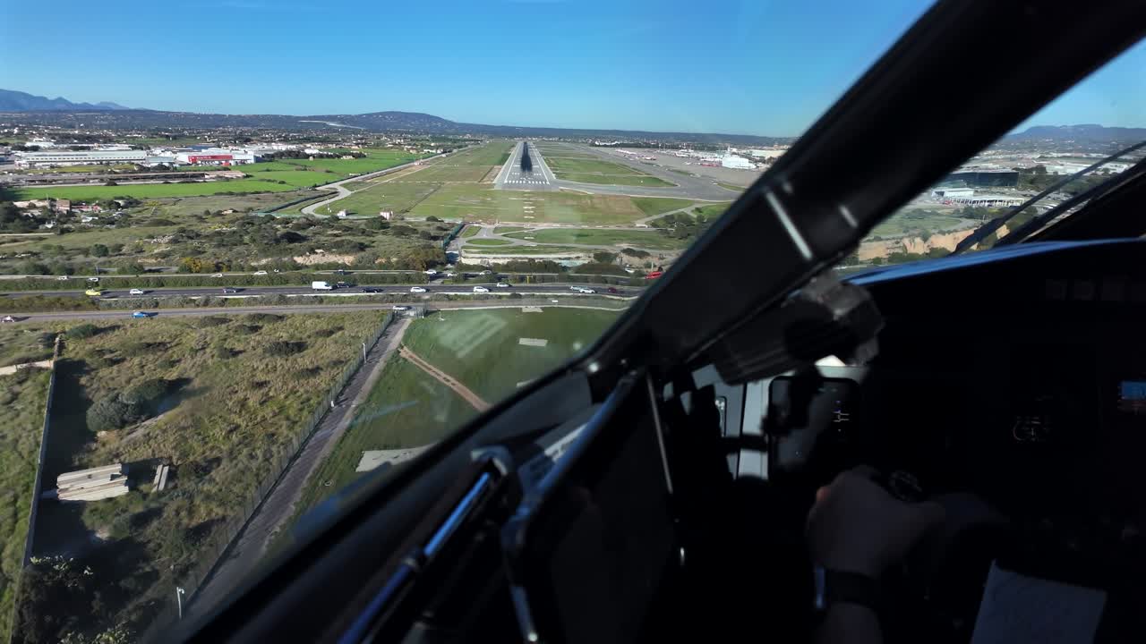 Pemandangan kokpit yang imersif, dengan kapten menerbangkan pesawat jet secara manual saat pendekatan akhir ke landasan pacu Bandara Palma de Mallorca di bawah langit biru