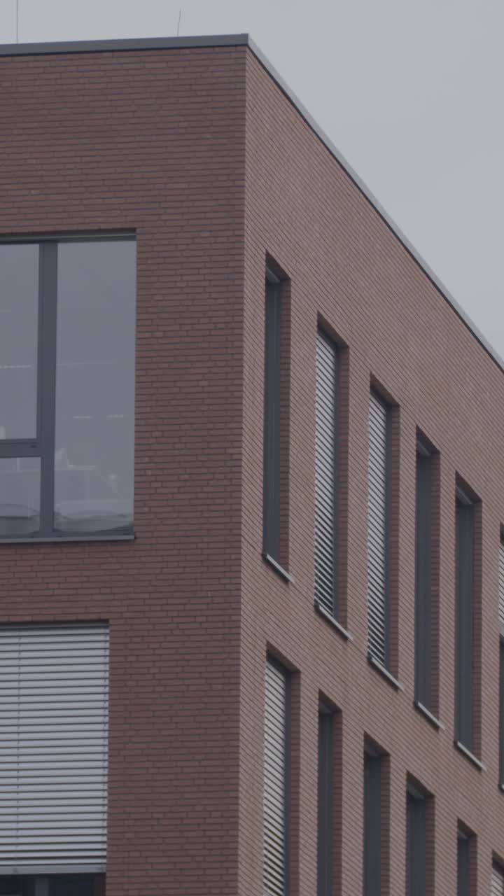 Modern brick building with large windows on cloudy day, urban setting