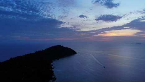 Vista-Aérea-Del-Océano-Y-La-Montaña,-Con-Un-Barco-Y-La-Puesta-De-Sol