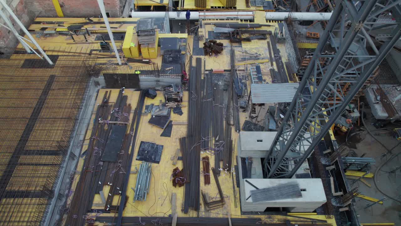 Work on foundations at construction site with metal reinforcements and tall crane