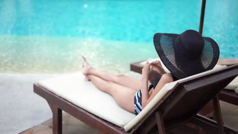 Asian-woman-sitting-in-solace-on-a-chaise-at-the-pool