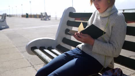 girl listening music while reading a book at beach 4k