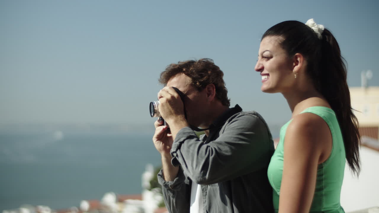 giovane coppia che scatta foto mentre si godono la vista del mare.