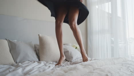 happy woman jumping on bed in hotel room having fun successful lifestyle celebrating enjoying luxury penthouse apartment