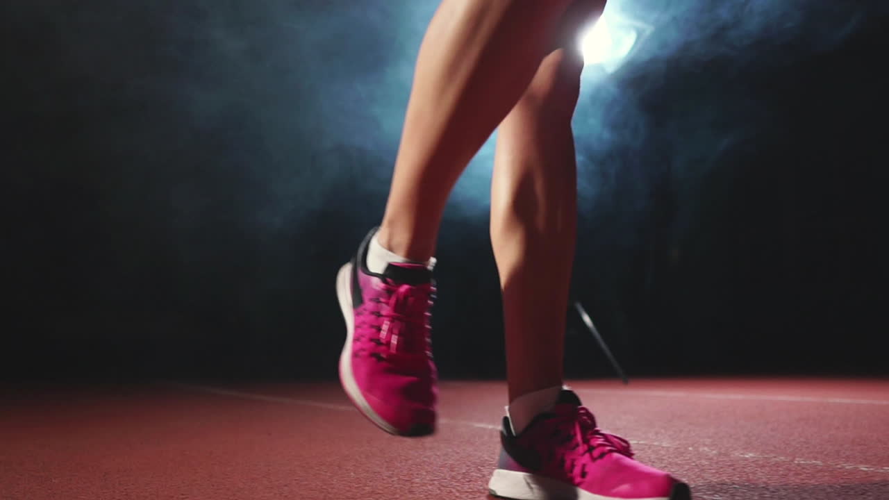 las piernas de primer plano en zapatillas de deporte los atletas están corriendo almohadillas en la pista del complejo deportivo y correr en cámara lenta
