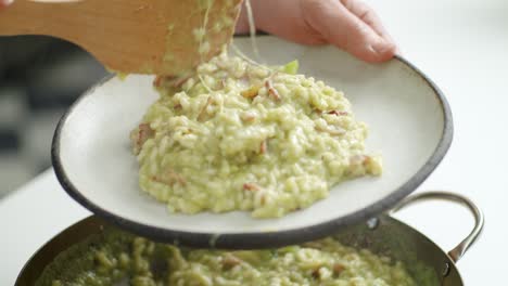 faceless chef serving risotto on plate