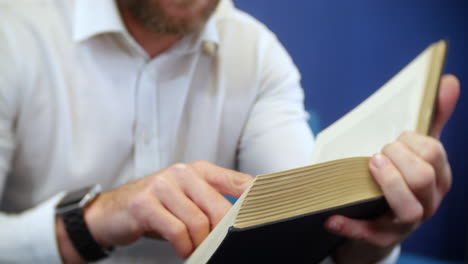 a man holding and reading a book with fingers following the lines