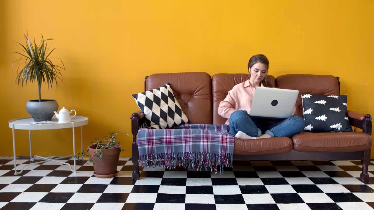 mujer trabajando en una computadora portátil en un sofá en una elegante sala de estar